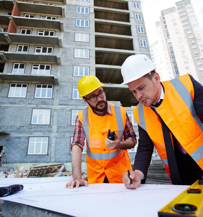 Modern engineer pointing at sketch in blueprint while explaining it to colleague