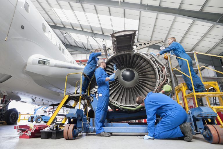Engineers assembling engine of passenger jet in hangar